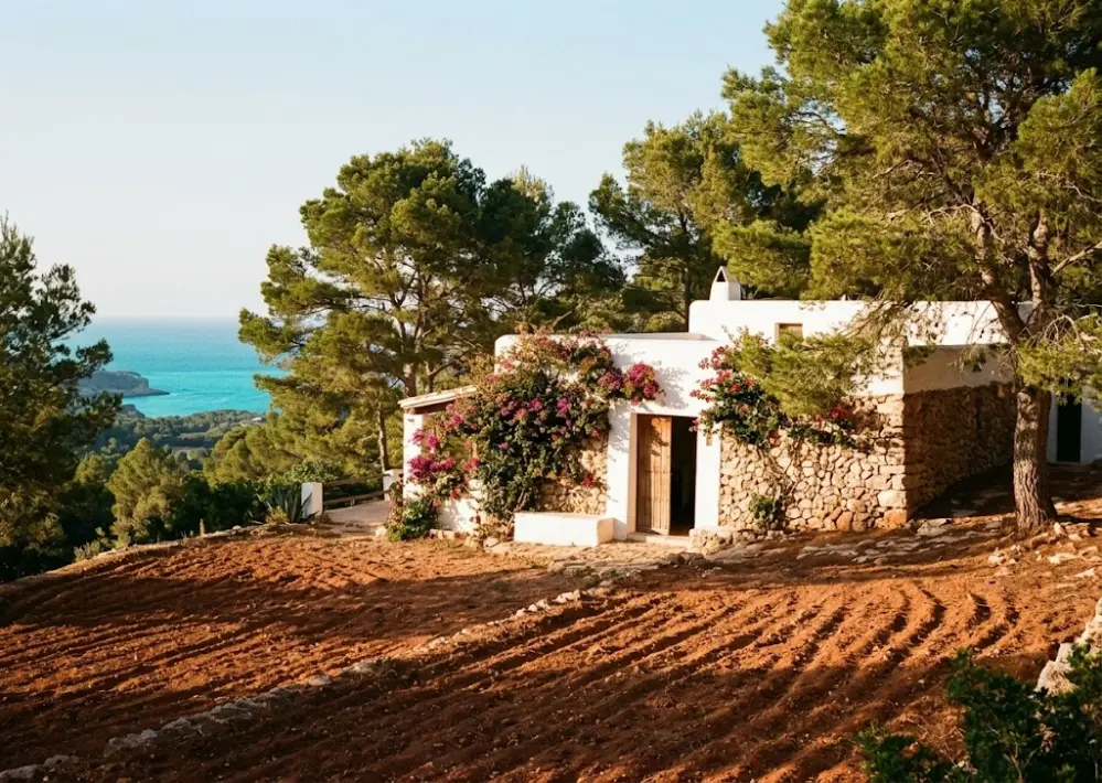 Traditional Ibiza finca farmhouse with red earth landscape, representing Amba Isis Jackson's childhood