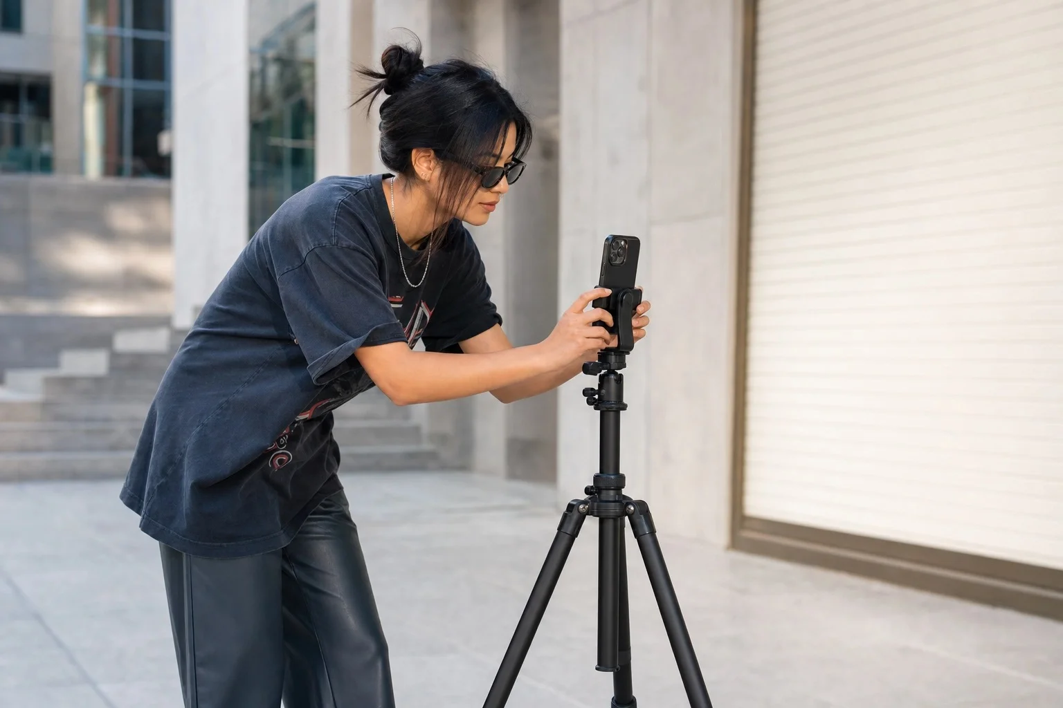 Person setting up tripod for full-body outfit photos using smartphone camera outdoors